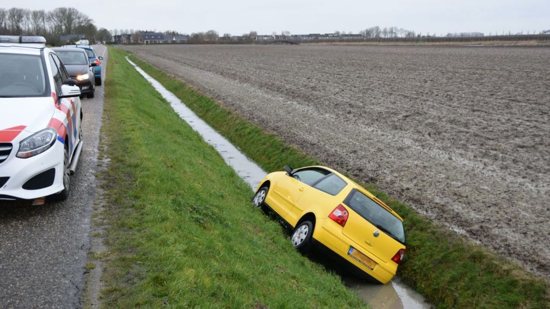 Een politiewagen neemt poolshoogte op de plek waar de auto in de sloot belandde.