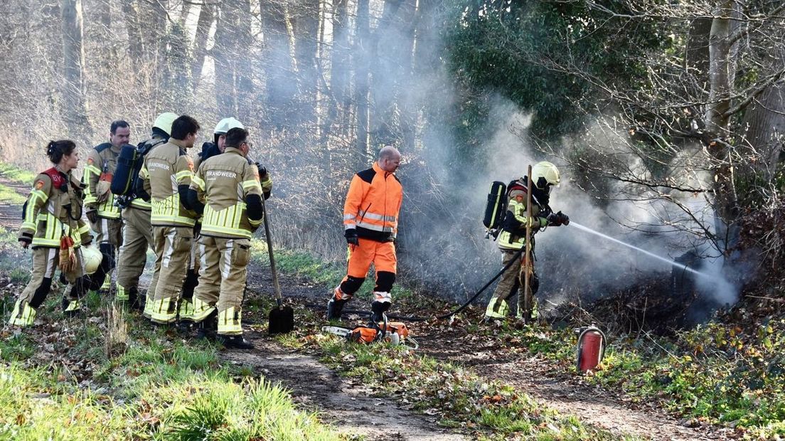 Brandweer blust brand in houtwal op woonperceel in Olst