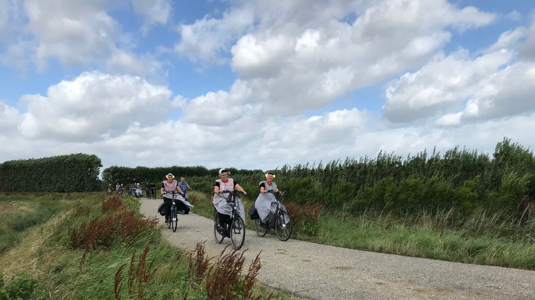 Vrouwen in Bevelandse dracht op de fiets.