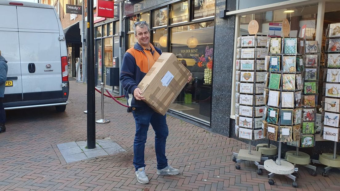 Kees druk aan het werk in de Schoolstraat, links zijn bezorgbus