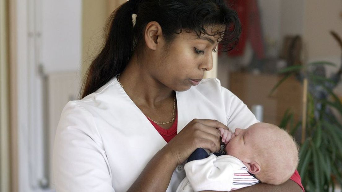 Een pasgeboren baby wordt verzorgd door de kraamverzorgende.