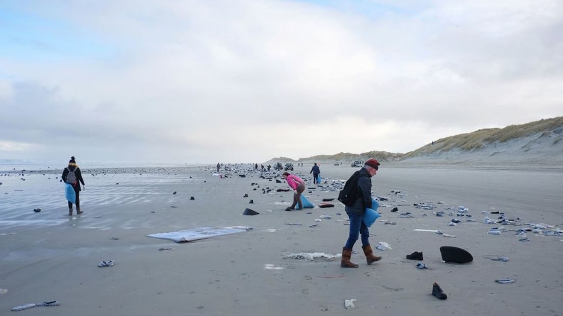 Mensen helpen na de containerramp mee om rommel op het strand van Ameland op te ruimen.