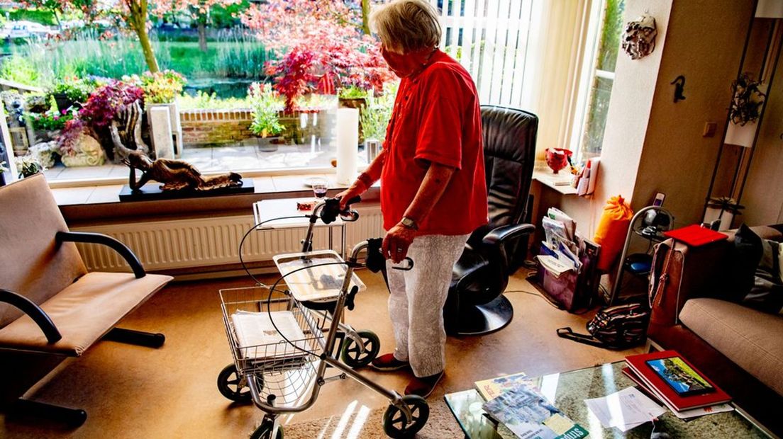 Een vrouw met rollator in haar woning.