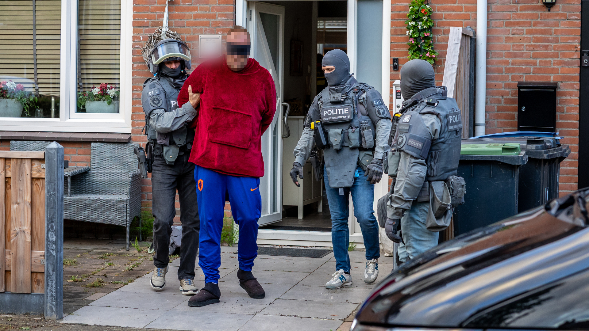 Bij een van de invallen in Hellevoetsluis werd een verdachte geblinddoekt afgevoerd.