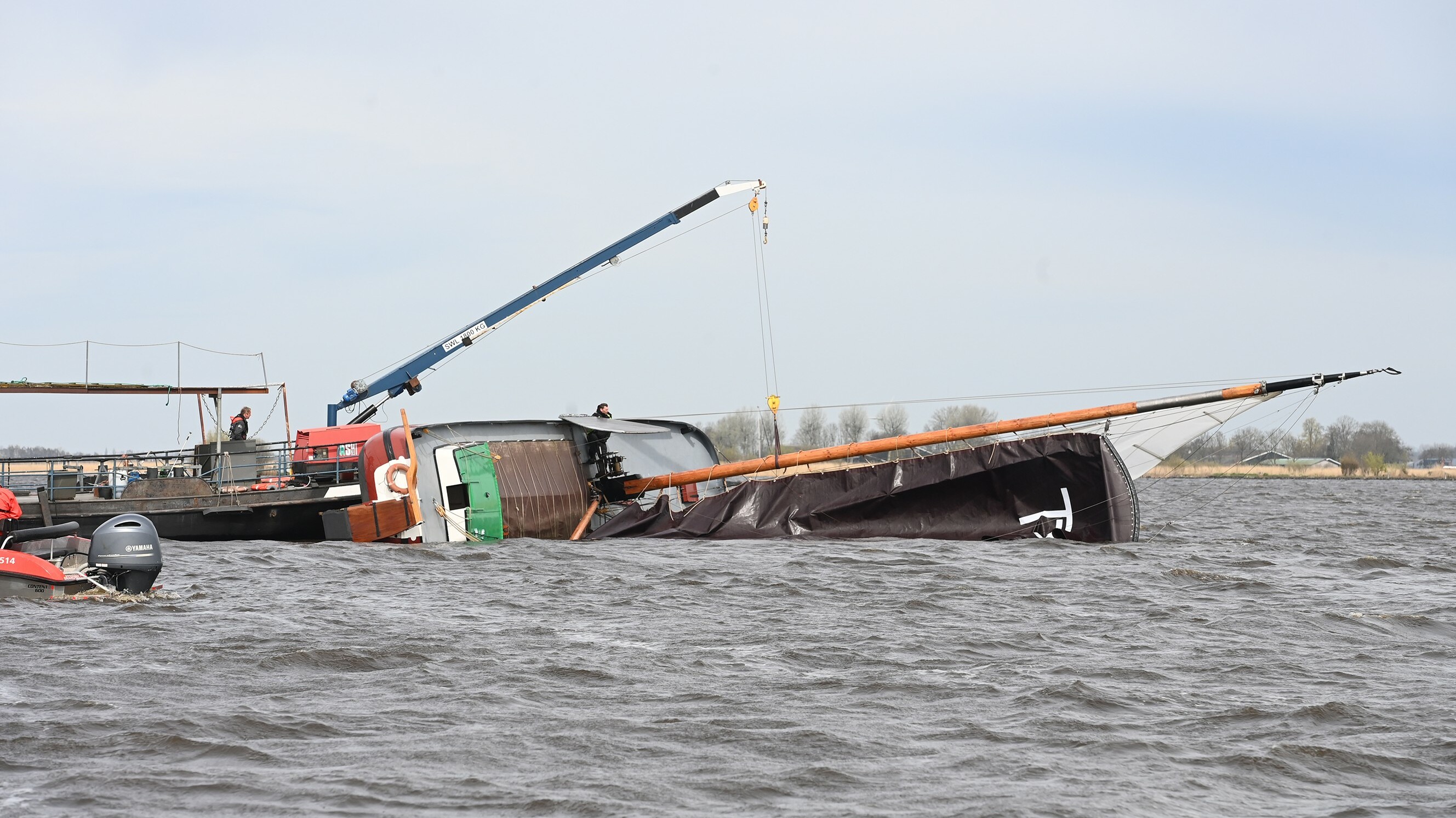 Met een takel wordt geprobeerd het skûtsje weer overeind te zetten