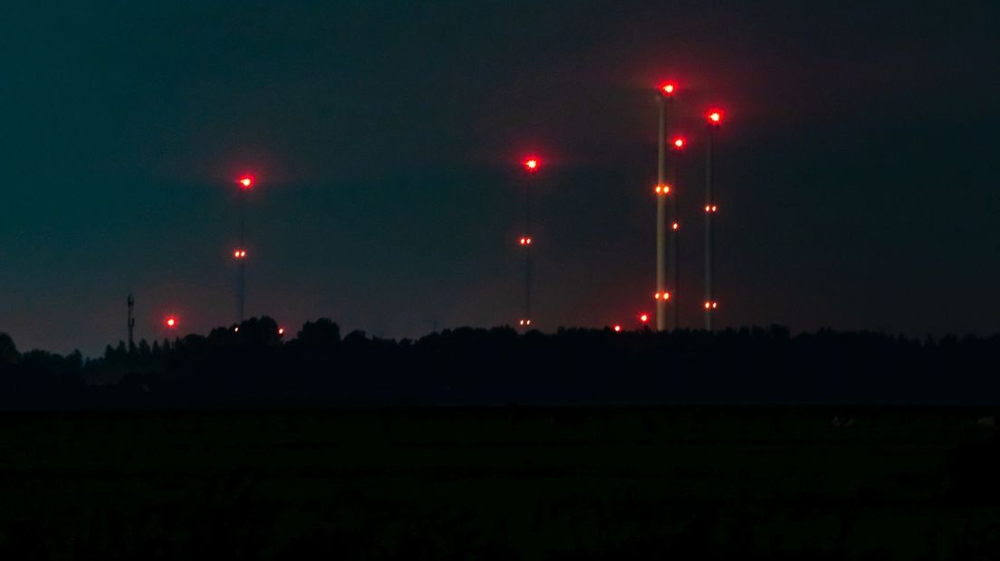 De rode verlichting op de windmolens aan de overkant van de Eem in Flevoland.