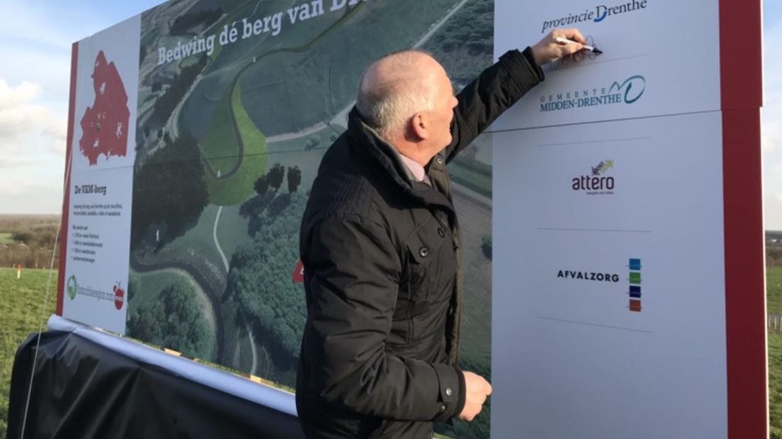 Gedeputeerde Henk brink zet zijn handtekening op een informatiepaneel op de VAM-berg (Rechten: RTV Drenthe)