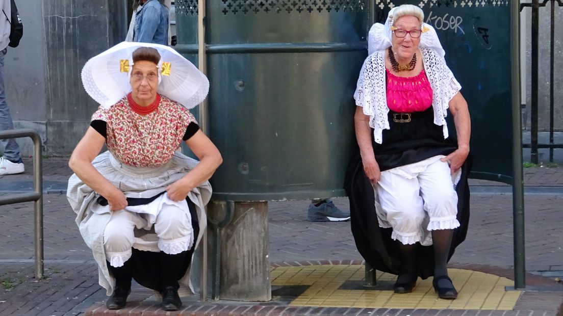 Dames in Zeeuwse klederdracht bij krul-urinoir in Amsterdam