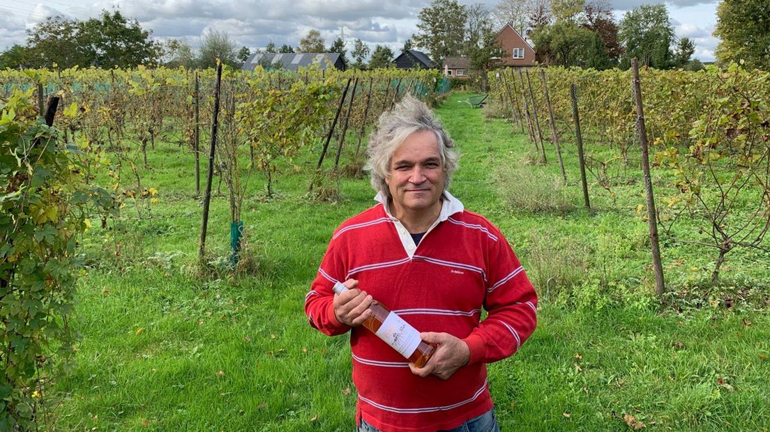 Ralph Mulders in zijn wijngaard met een fles oranjewijn