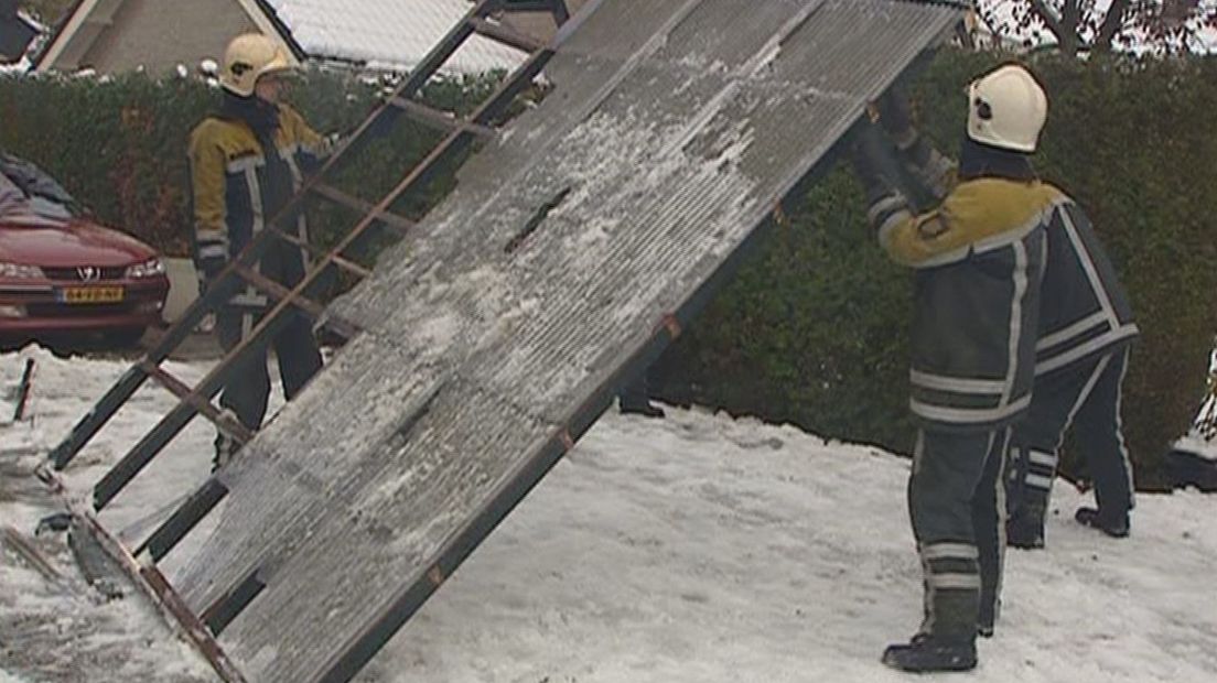 Brandweermannen bij een dag van een dak van een carport die was ingestort