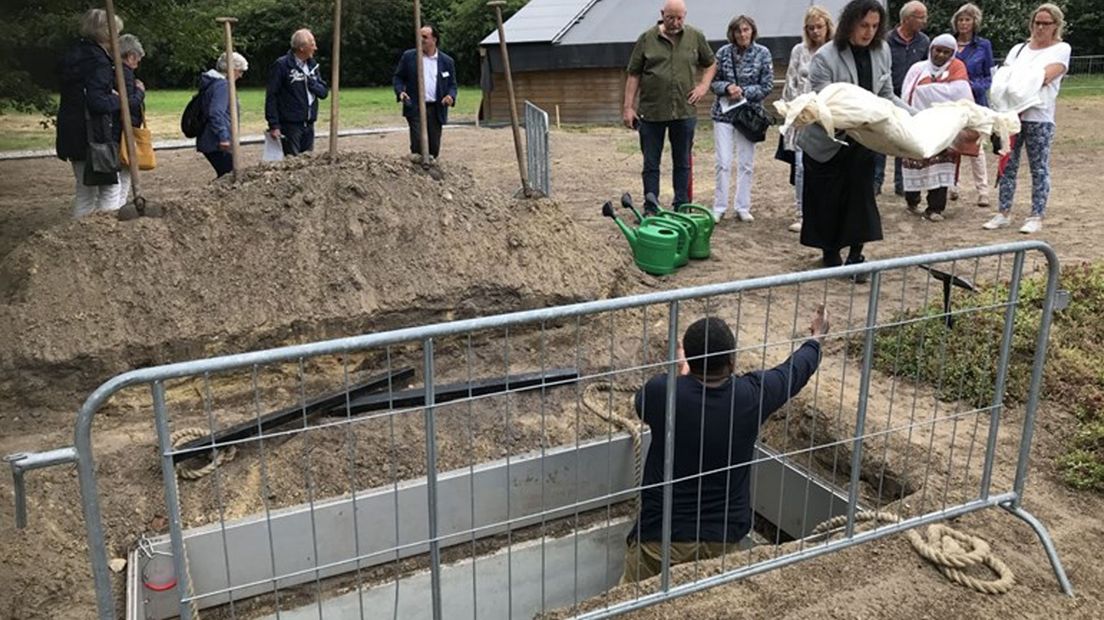 Met een pop wordt getoond hoe mensen worden begraven.