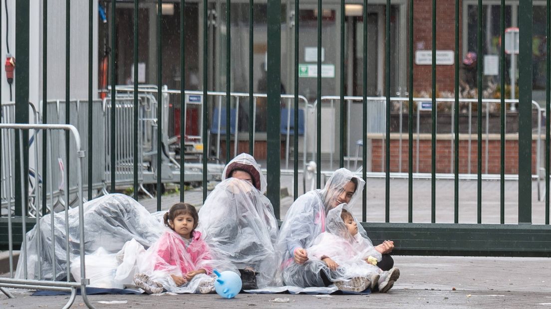 Mensen met kinderen in de regen voor de poorten van het aanmeldcentrum, donderdagavond