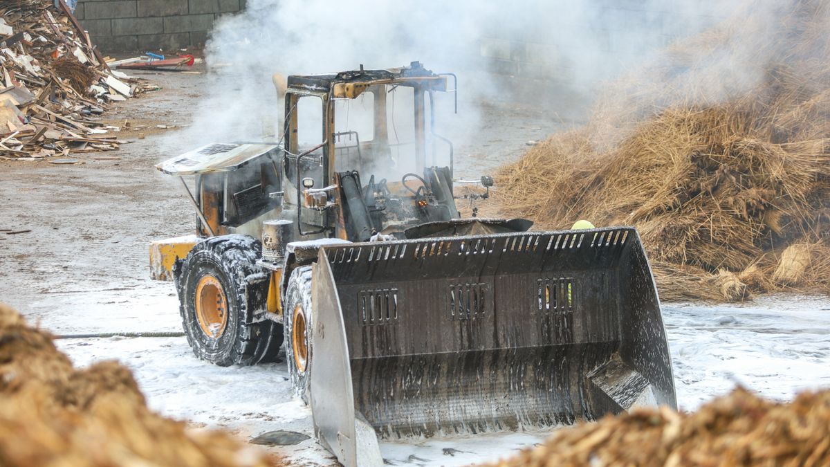 Shovel in brand vlak bij bult hout in Drachten