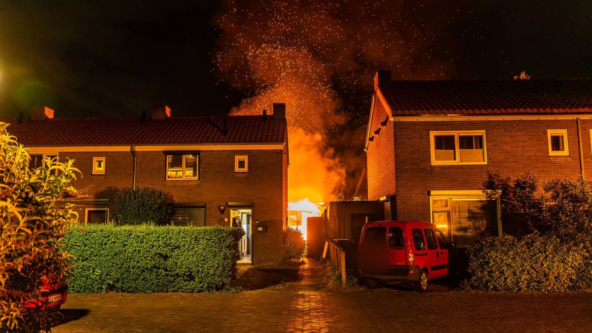 Vlammenzee achter woning, buurman blust vanaf dak