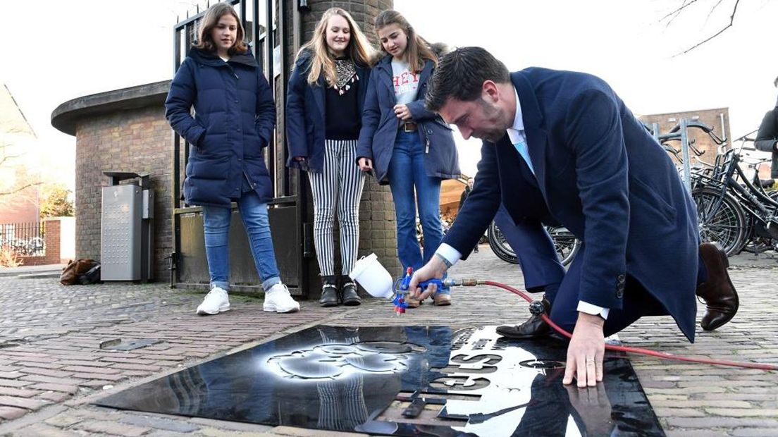 Wethouder Van Asten plaatst de krijttekening bij de school