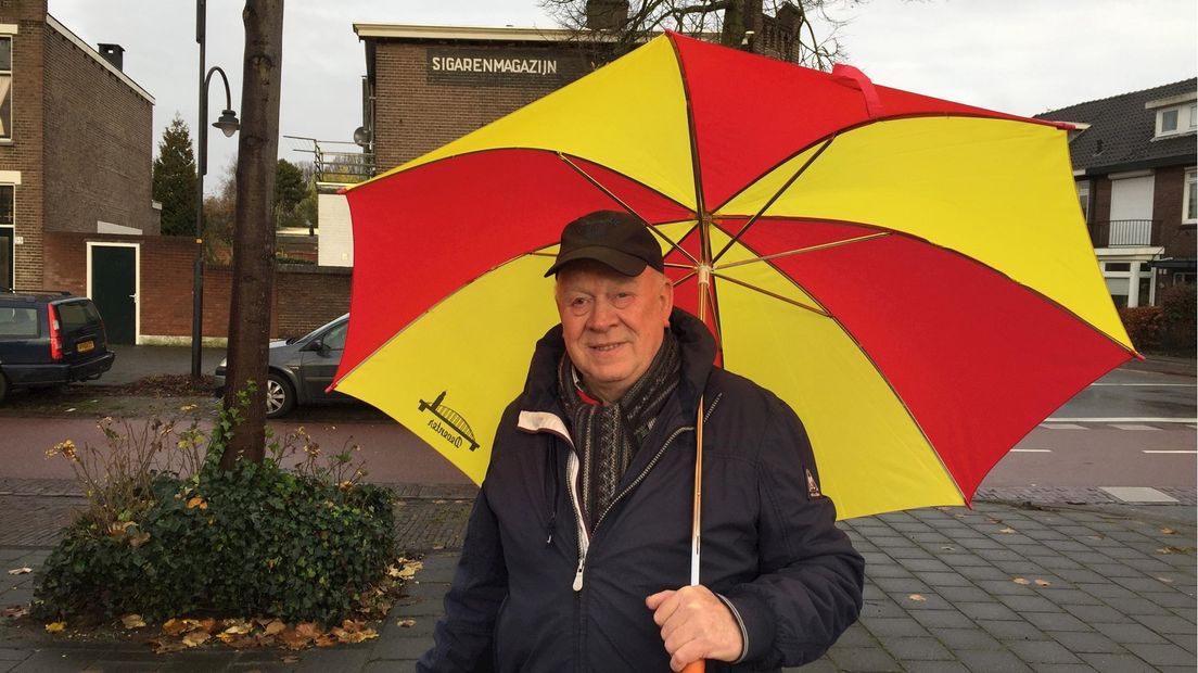 Go Ahead Eagles-supporter Willem de Witte: schuilen onder rood-gele paraplu
