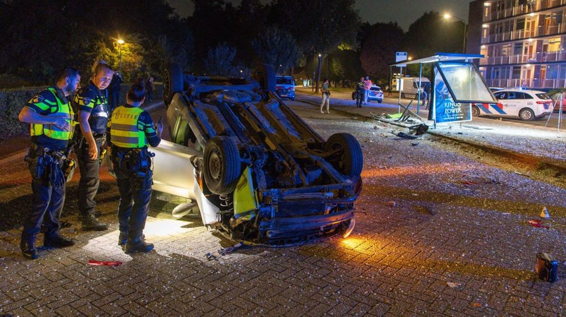 Brokstukken van de auto en abri lagen naderhand verspreid over de straat.