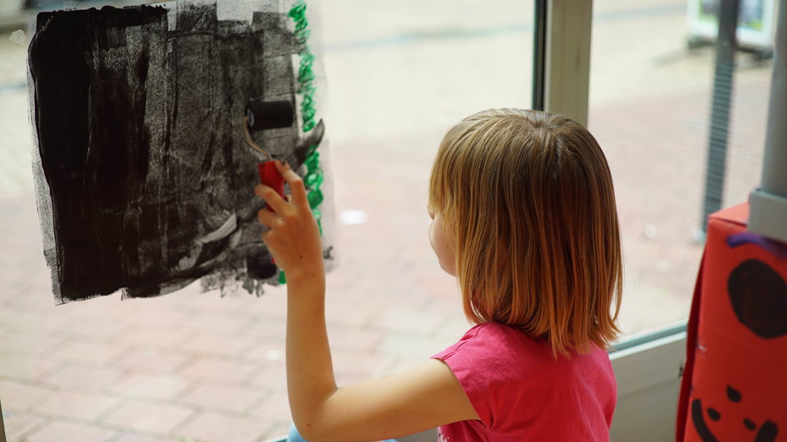 Een kind beschildert de ramen van het kennisatelier. (Rechten: Steven Ophoff/RTV Drenthe)