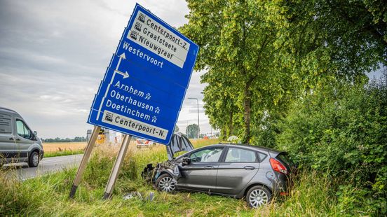 Auto ramt lantaarnpaal en wegwijzerbord, bestuurder gewond
