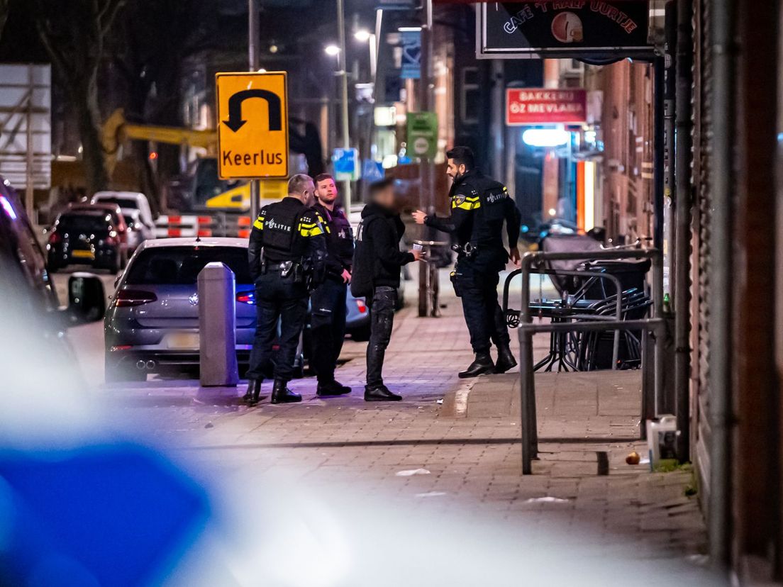 De politie praat met een man na het schietincident in café 't Halve Uurtje