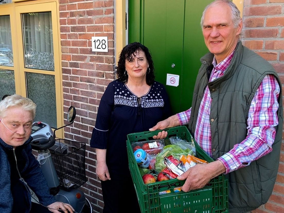 John (rechts) deelt voedselpakket uit aan Ger en Maria