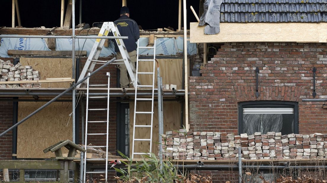 Een huis met bevingsschade in de steigers (archief)