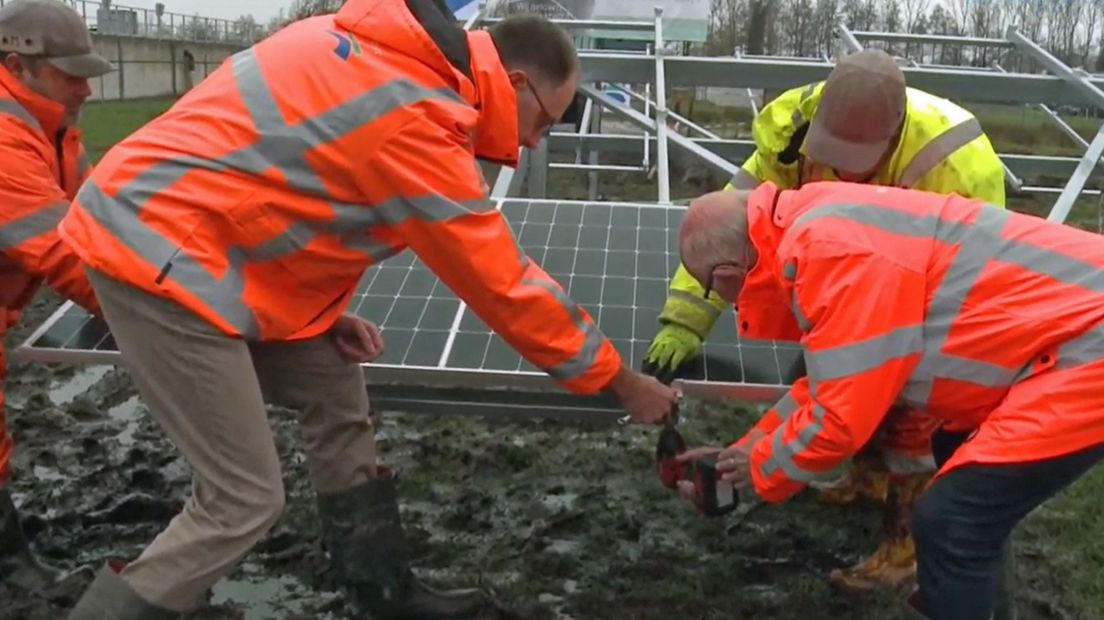 Waterschapsbestuurder Herman Beerda (rechtsonder) plaatst het eerste zonnepaneel