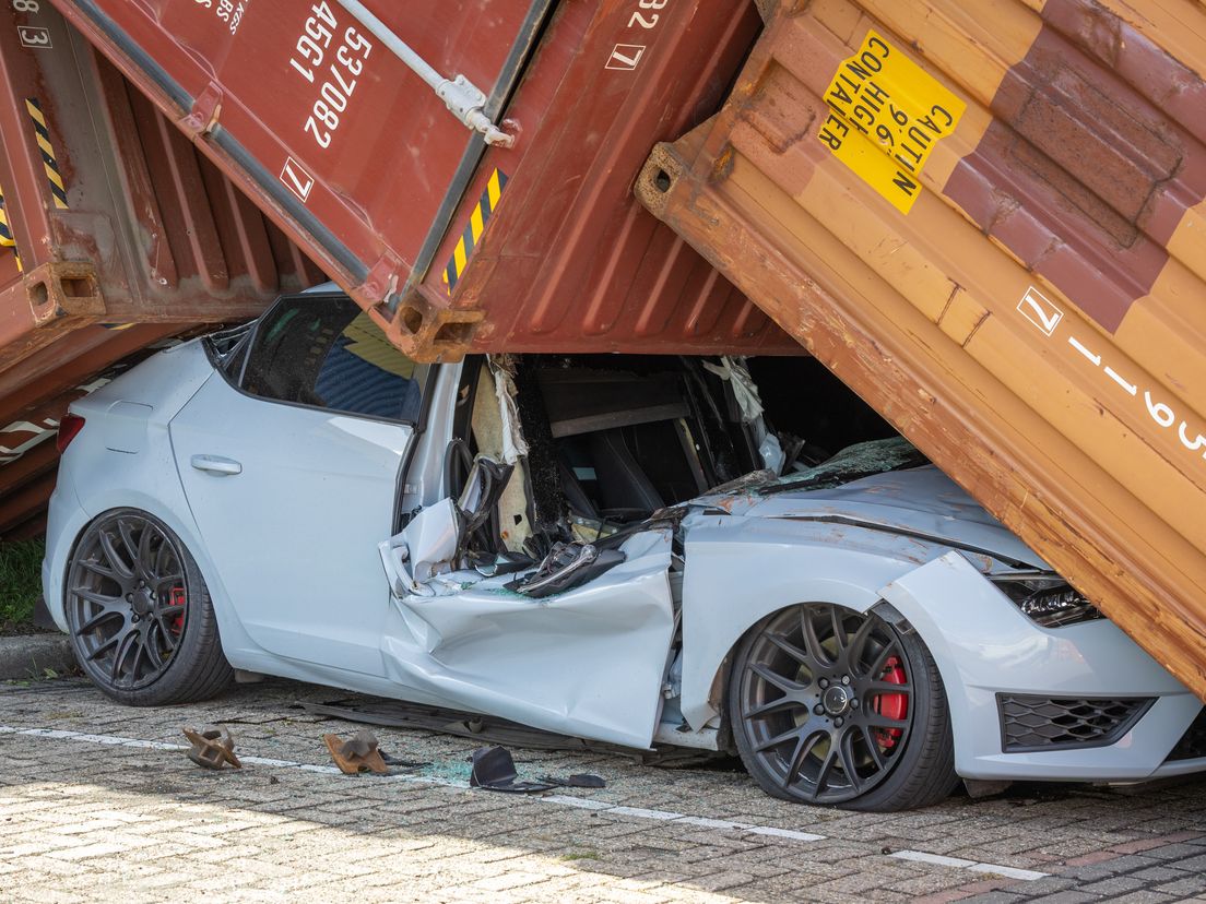 De omgevallen containers hebben de hele voorruit van de auto laten verdwijnen.
