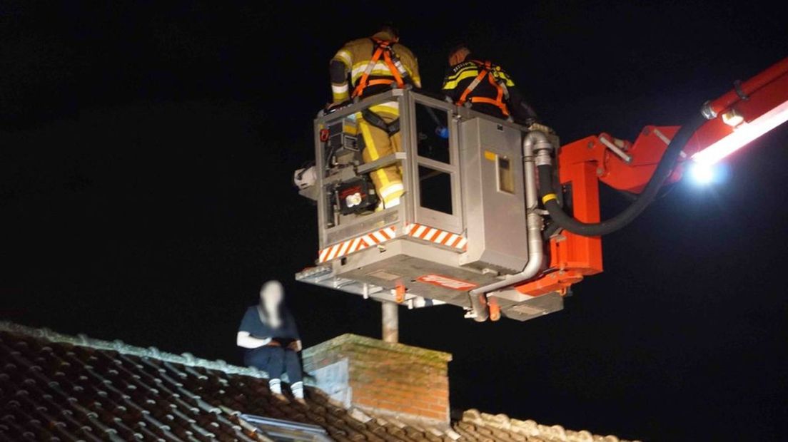 De brandweer haalt de gevluchte vrouw met een hoogwerker van het dak