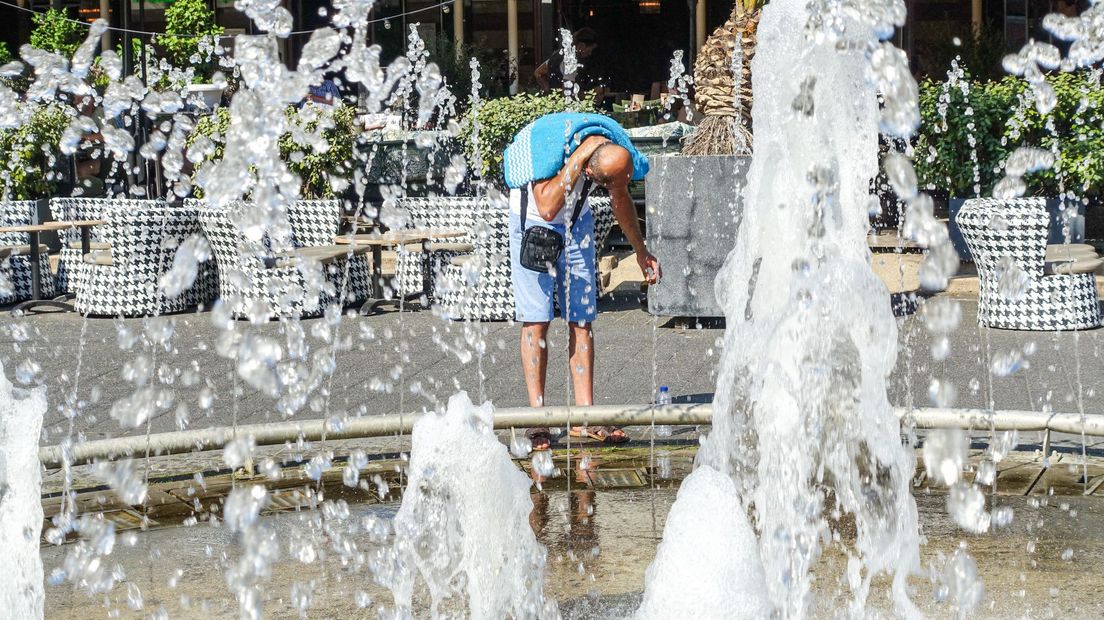Een man zoekt verkoeling tegen de warmte bij de fonteinen van Scheveningen