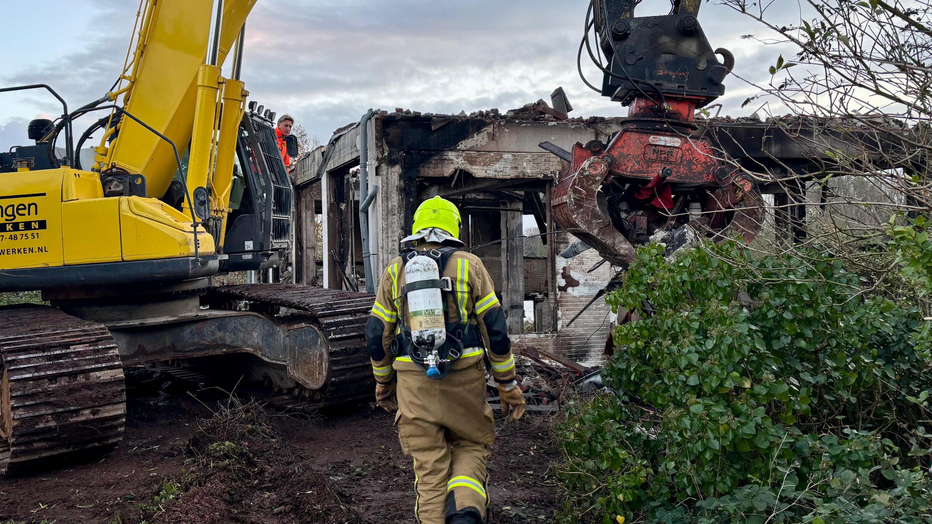 Een kraan is de restanten van het uitgebrande huis aan het slopen