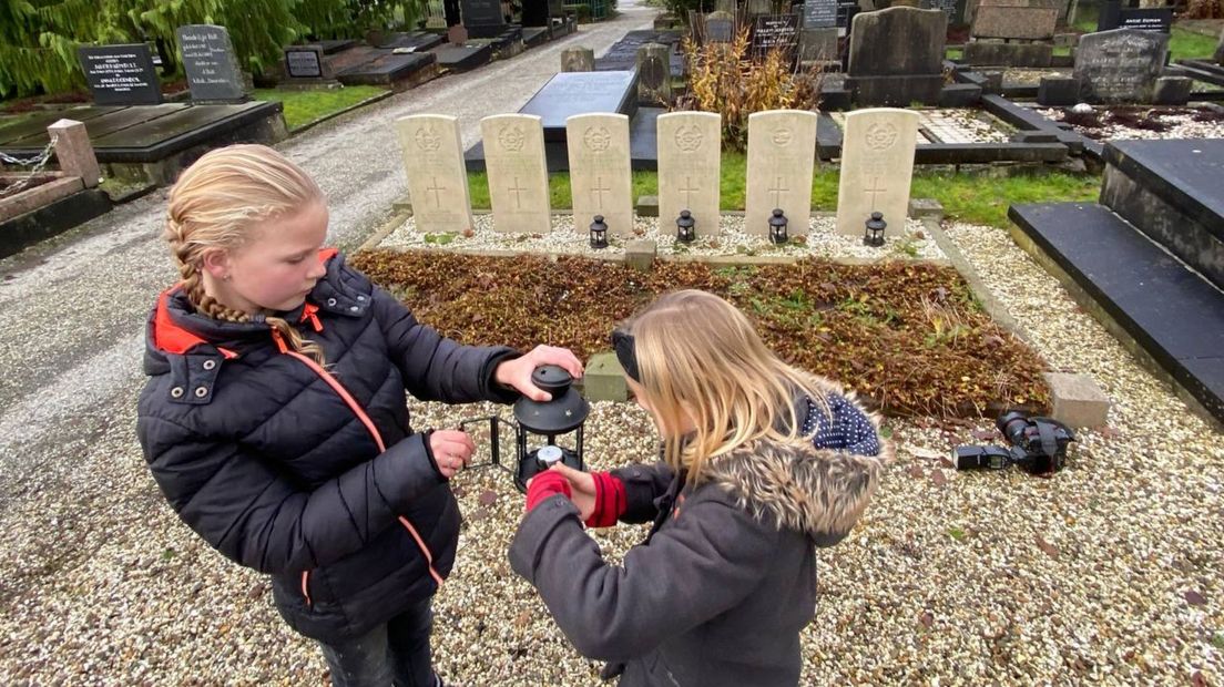 Twee meisjes steken kaarsjes aan op de begraafplaats van Ten Boer