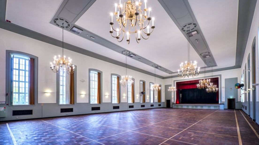 De theaterzaal met podium, parketvloer en kroonluchters is nog vrijwel in de originele staat.