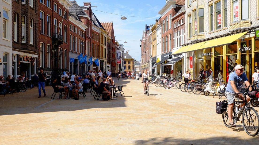 Terras, voetgangers, fietsers en bezorgscooters door elkaar op de Brugstraat in Groningen