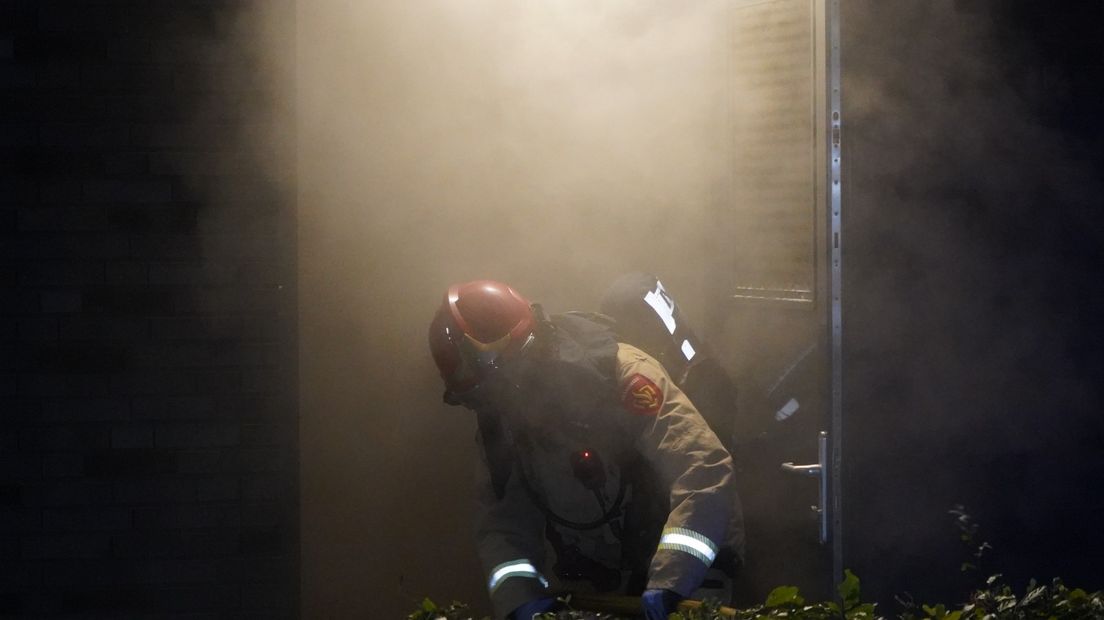 Brandweer legt brandslangen uit in de rook