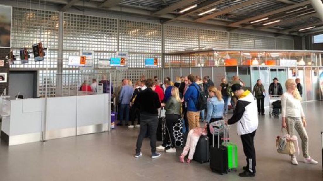 Een rij van reizigers op Airport Eelde in mondkapjesloze tijden