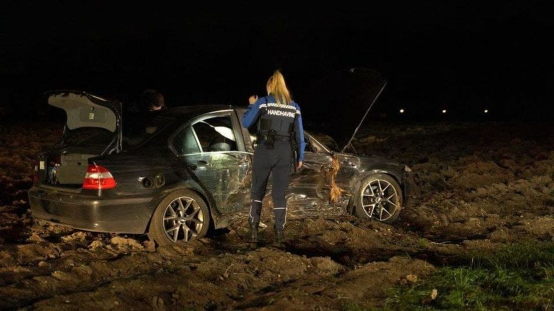 Een handhaver bij de zwaar beschadigde auto.