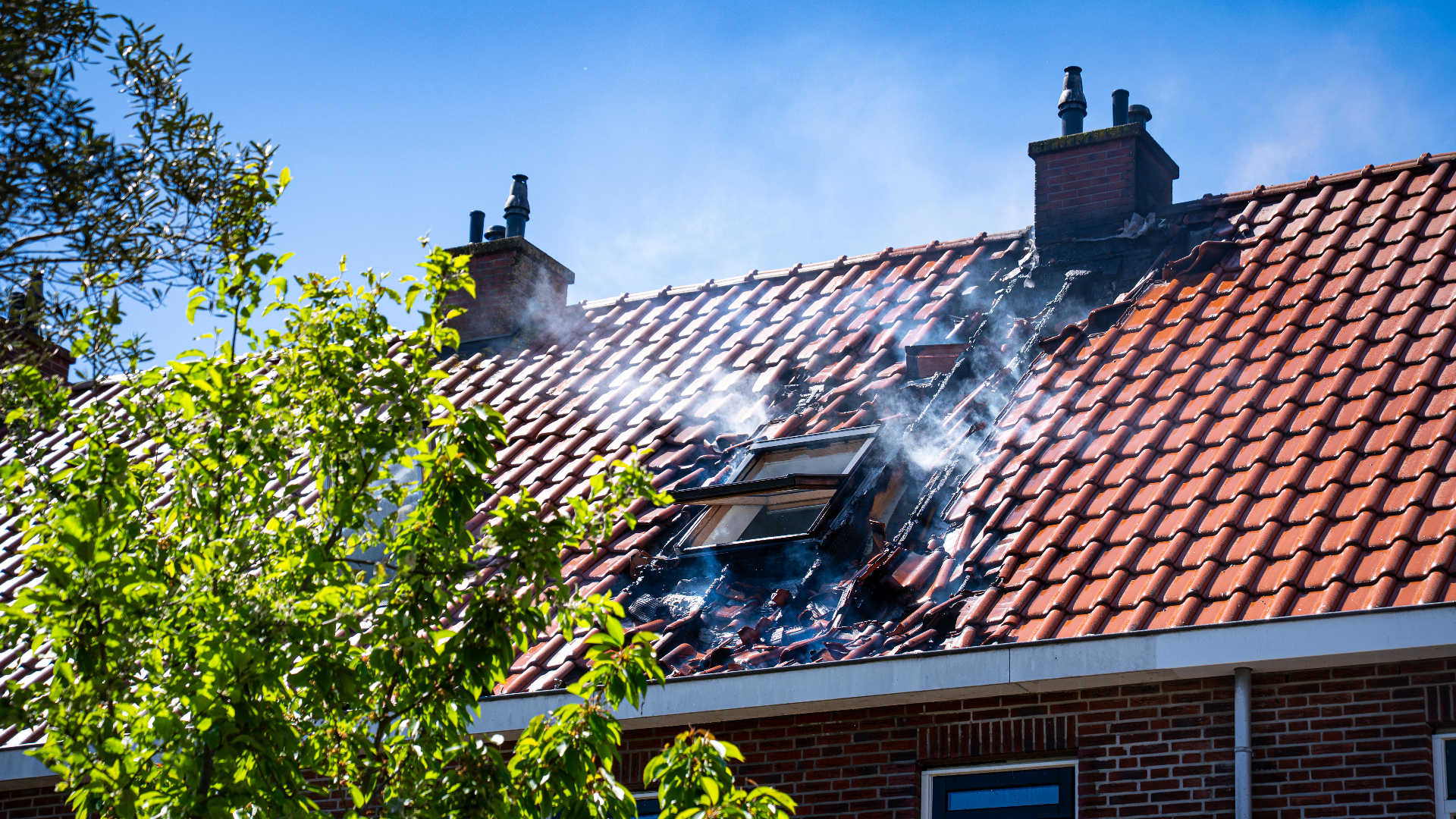 Vlammen sloegen uit het dak van de woning.