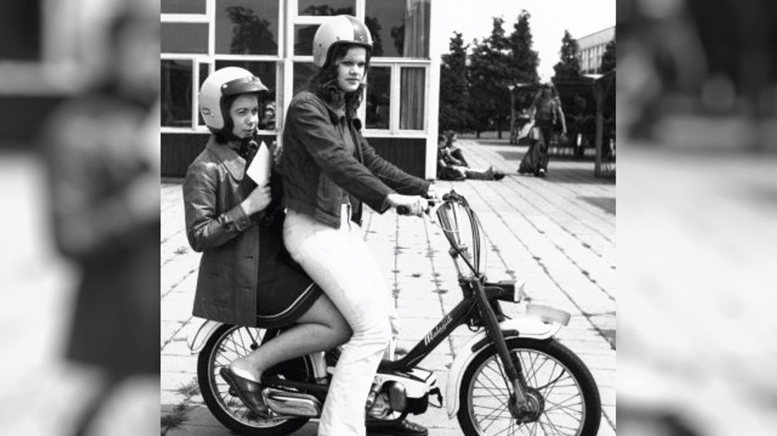 Twee jonge vrouwen op een brommer met een helm op