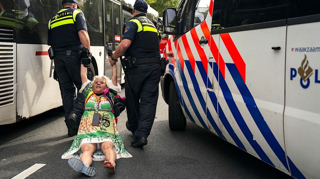 Een demonstrant wordt door de politie van de A12 gehaald