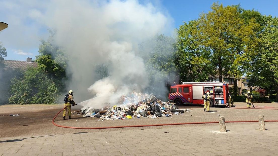 Brandweer blust afval op straat in Goor