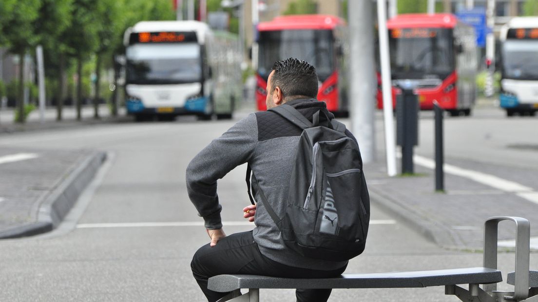 Een reiziger wacht op de bus bij het busstation op Leiden Centraal