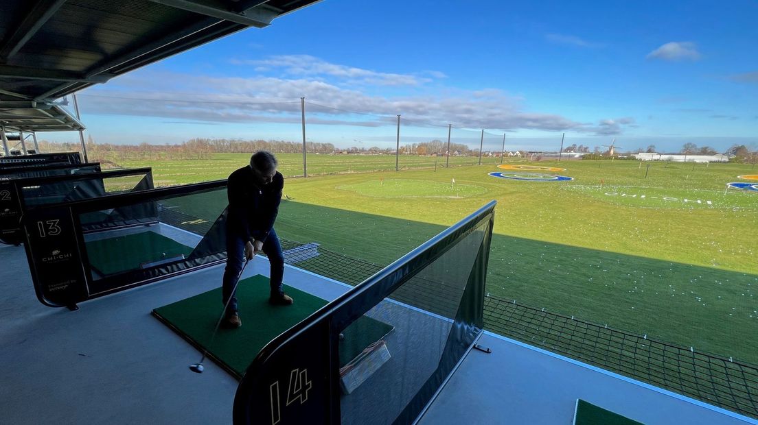 Een golfers slaat af van de driving range.