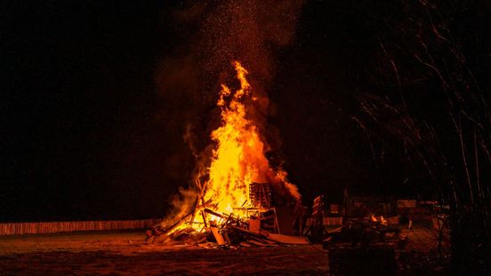 Grote houtstapel in brand, rieten dak woning ternauwernood gespaard