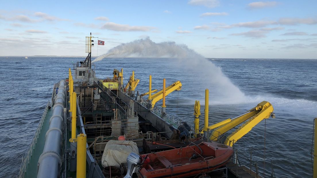 Een baggerschip is bezig met de vaargeul.