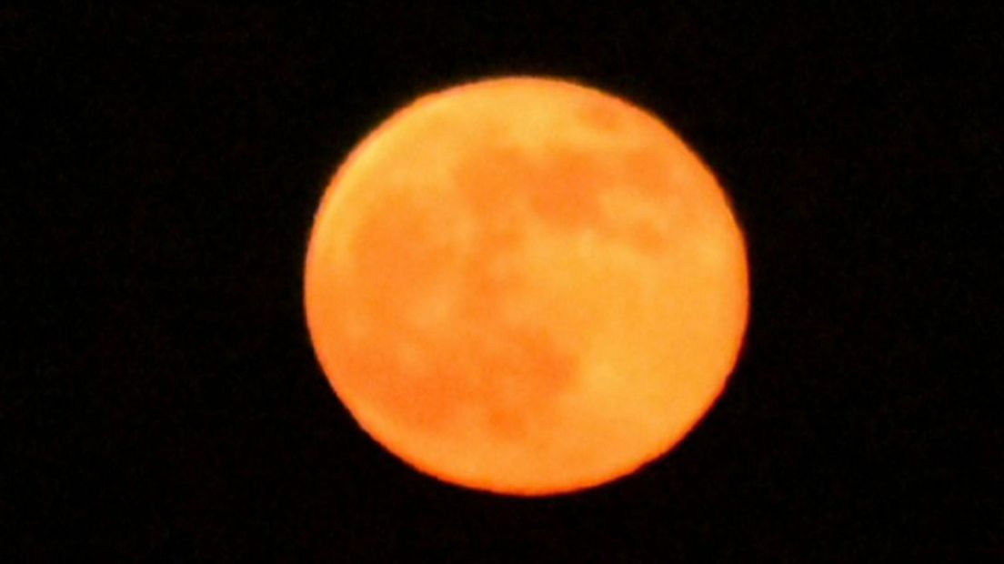De maan kleurde door de lage stand oranje op Koningsdag