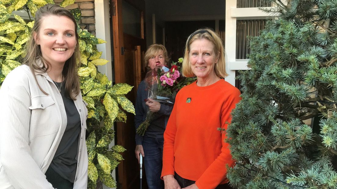 Simone (l), en José (r) verrassen buurvrouw Thea met een bloemetje voor al haar werk