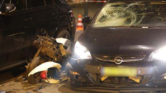 Aanrijding tussen onherkenbare politieauto en scooter, brokstukken liggen op straat. Aanrijding tussen onherkenbare politieauto en scooter, brokstukken liggen op straat.