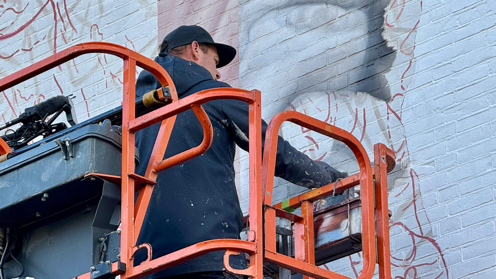 Ricardo van Zwol bezig met de hand van Beenhakker. De rode lijntjes zijn de droodles die de muralist als hulpmiddel gebruikt zodat het portret in verhouding blijft.