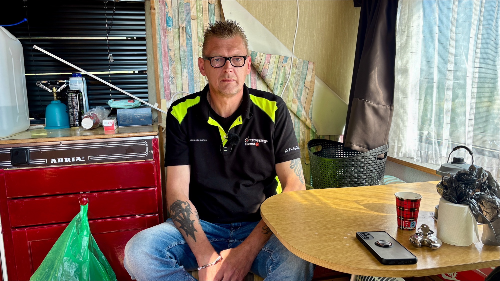 Henk zit op de bank in zijn caravan.